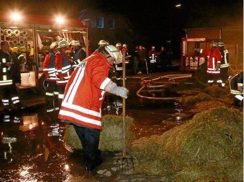 Brandeinsatz in Schönewörde: Feuerwehrmänner schaffen das Stroh vom Dachboden und löschen eventuelle Brandnester. Foto: © Feith